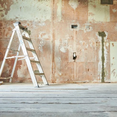 Home renovation with ladder and walls stripped of paint