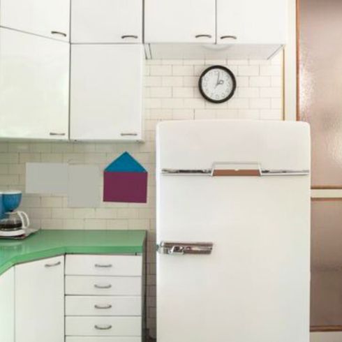 old, outdated kitchen with worn white cabinets and fridge