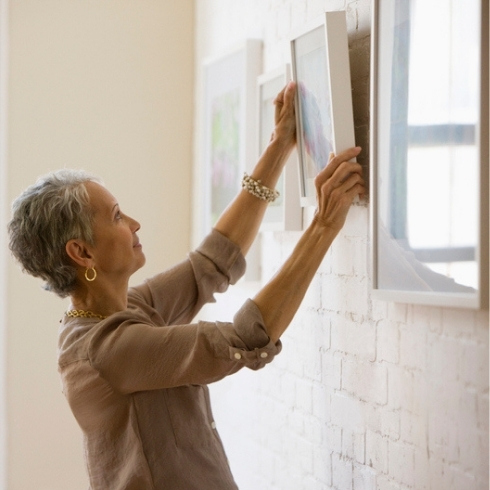 Mixed race woman hanging pictures on wall