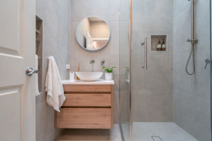 modern bathroom with concrete walls and wooden vanity sink with drawers