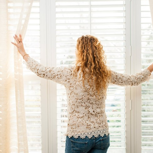 Woman opening curtains