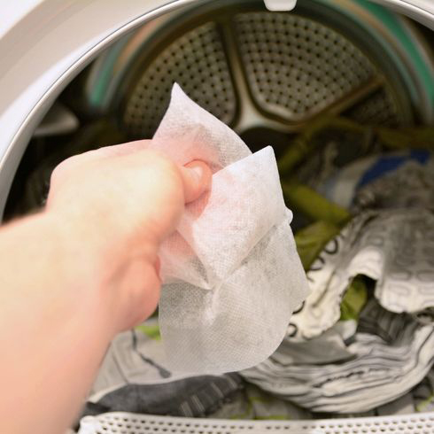 a person putting a dryer sheet into the dryer