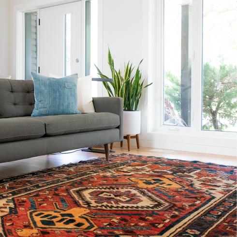 a living room with a gray couch and red carpets