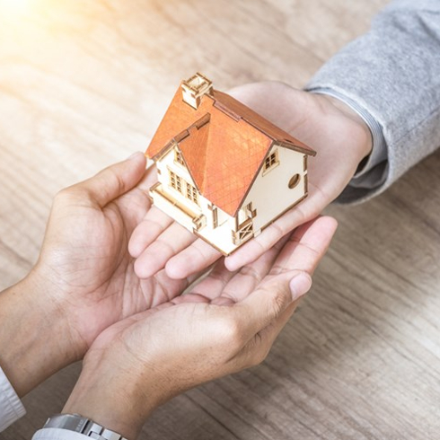 Hands passing house figurine