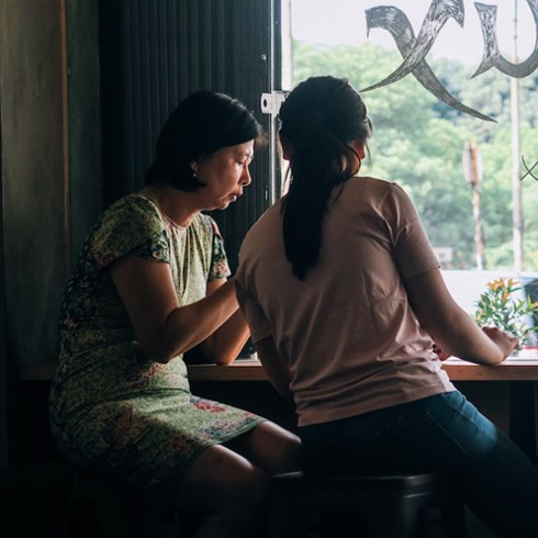 women talking in front of window