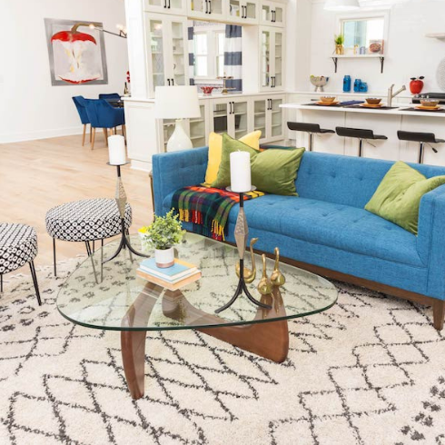 An open-concept living room with pops of colour in the bold furniture and area rug