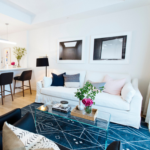 An open-concept East Coast apartment with minimal clutter and a white couch pushed up against the far wall