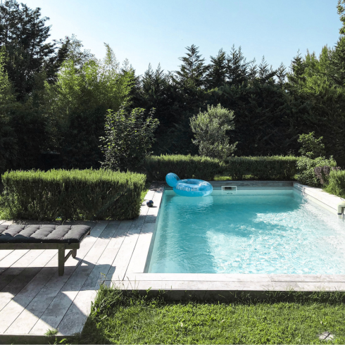 Backyard pool surrounded by trees and grass