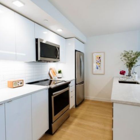 sleek modern white kitchen with light hardwood flooring