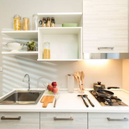 small white kitchen with cabinets and shelves