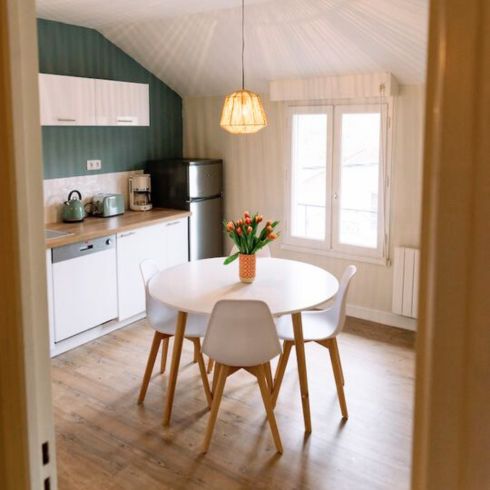 small kitchen with white round table and green feature wall