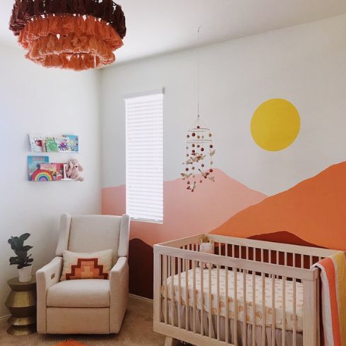 Nursery with painted bright mural of mountains and sun