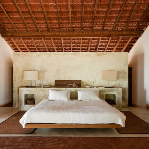 white bed in white bedroom with exposed beams at ceiling