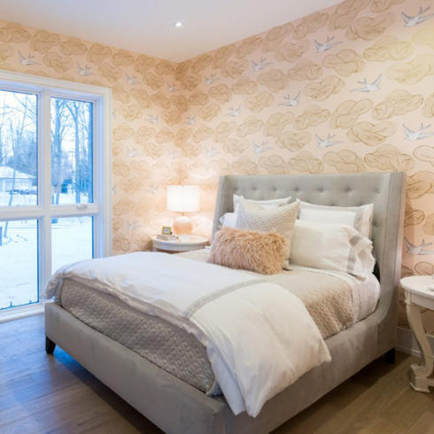 peach bedroom with bird wallpaper and grey bed