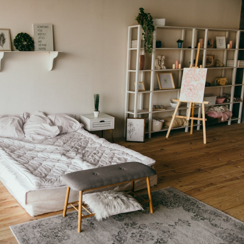 white bed in white bedroom with white shelving and grey rug