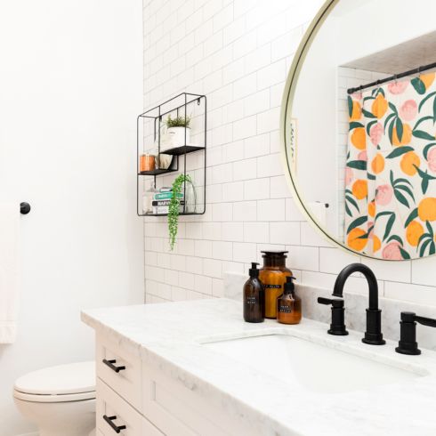 Modern white bathroom with large white vanity, black fixtures and gold round mirror