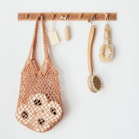 wooden hooks with bag and loofahs on white wall