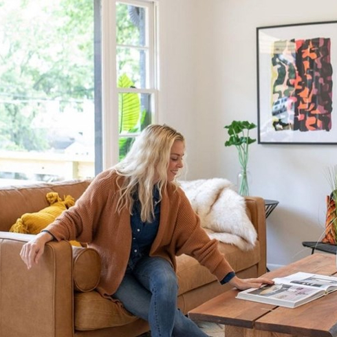 Kortney Wilson sitting on a couch reading a coffee table book