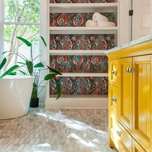 Yellow bathroom cabinet and bookshelf with bold wallpaper print