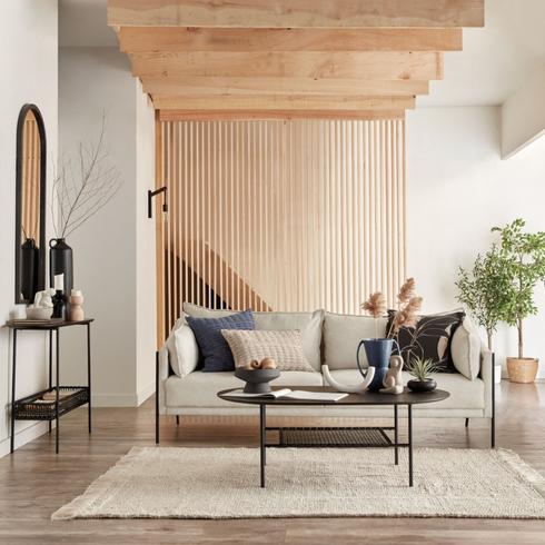 Modern living room with wooden slate accents, a rug, chair and black console table