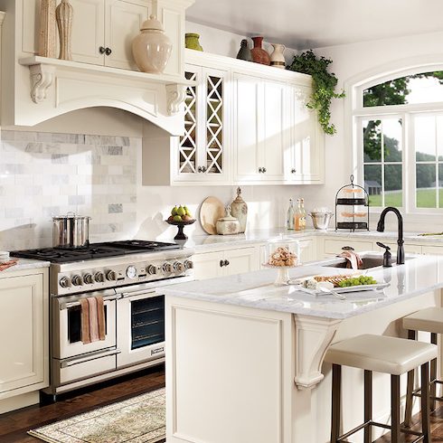 Beautiful classic white kitchen, painted in BEHR Cameo White MQ3-32 and Swiss Coffee 12, featuring a large centre island with a sink, marble countertops and two white leather stools