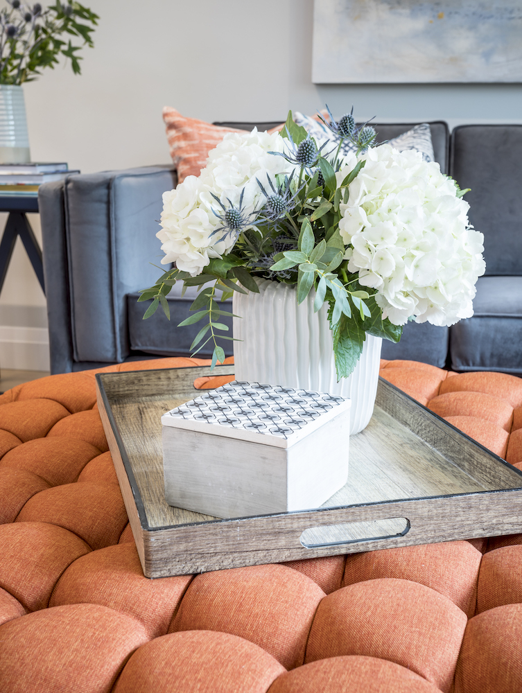 Orange ottoman with floral arrangement.