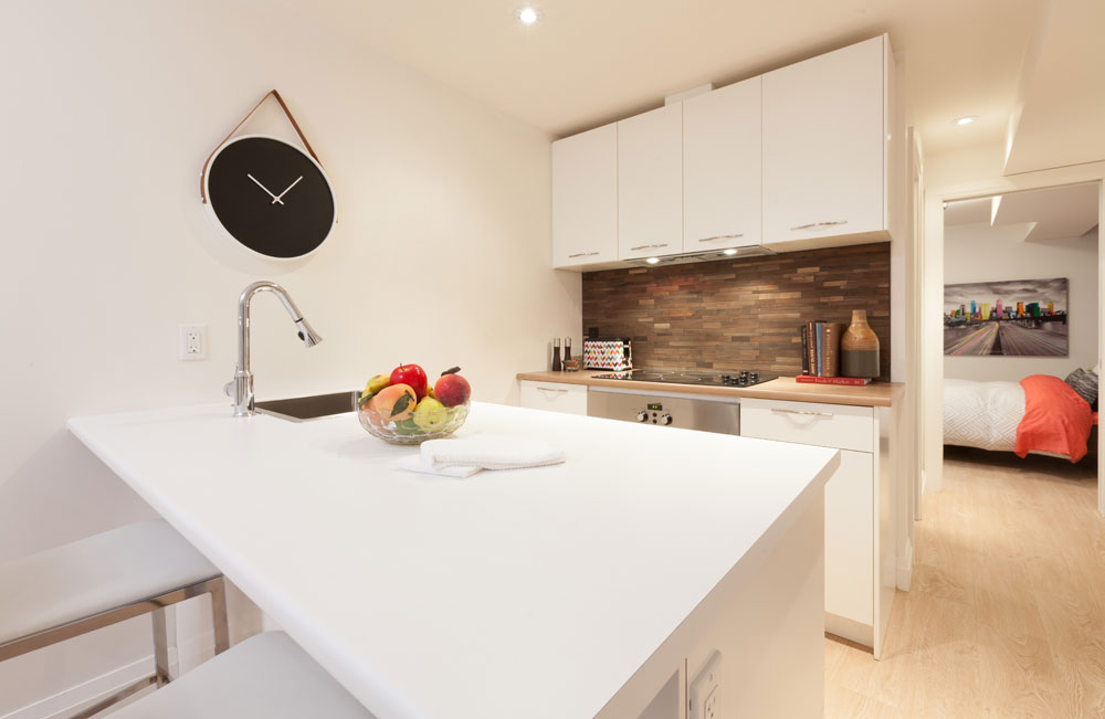 A textural earthy backsplash brings warmth to this elegant basement kitchen by Scott McGillivray