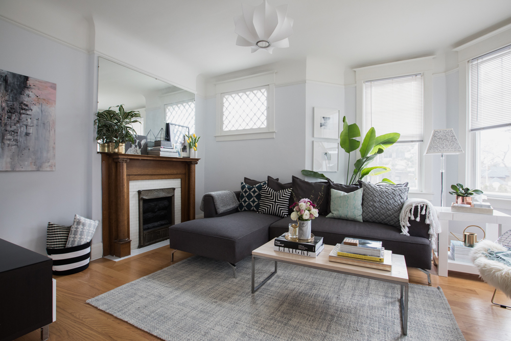 dark grey sectional in front of wood tone fireplace with unframed mirror above