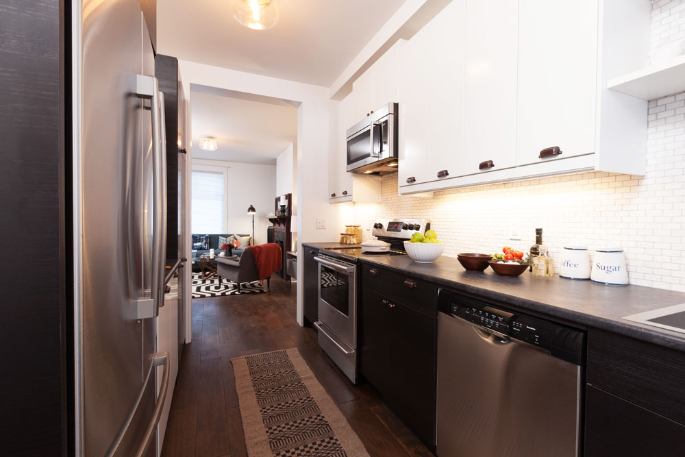 Galley kitchen with small subway tile and grey grout lines.