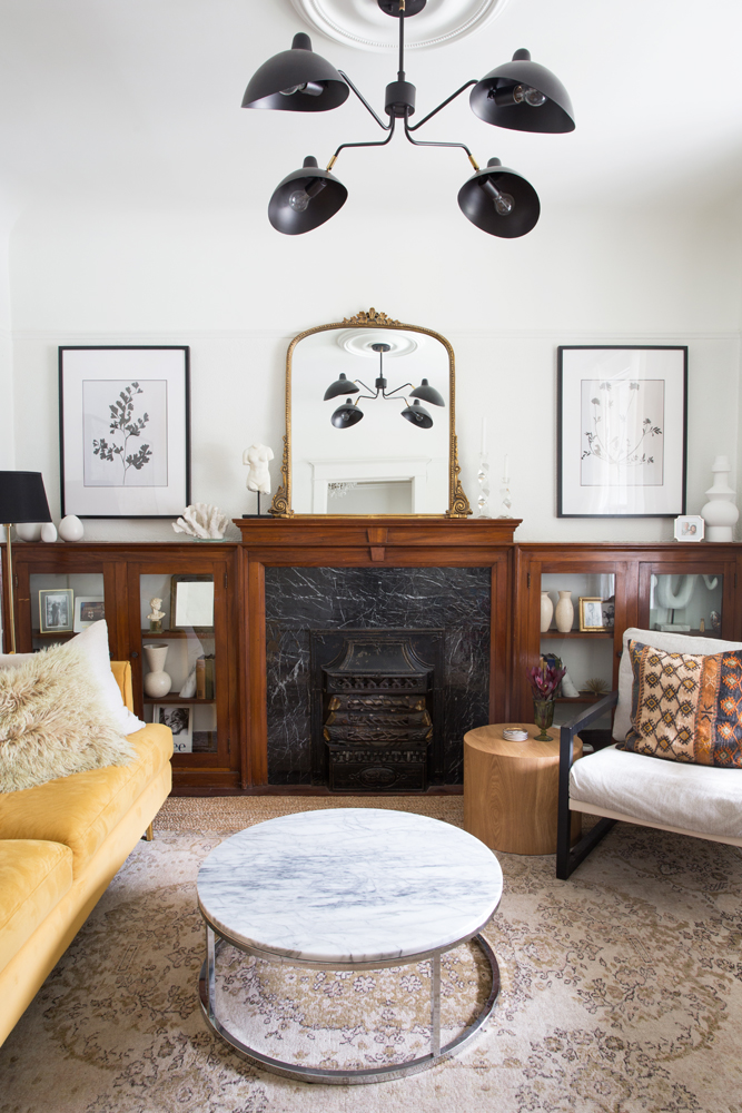 Fireplace mantel adorned with vintage pieces and gold French mirror.