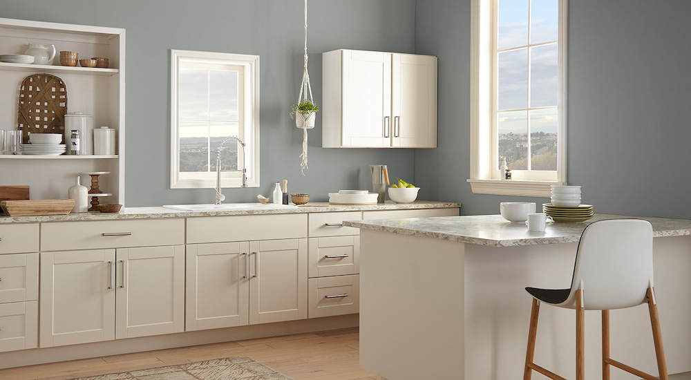 A modern kitchen with a kitchen island topped with grey stone countertops, white cabinets painted in BEHR Silky White PPU7-12, and walls painted in BEHR Watery HDC-CT-26