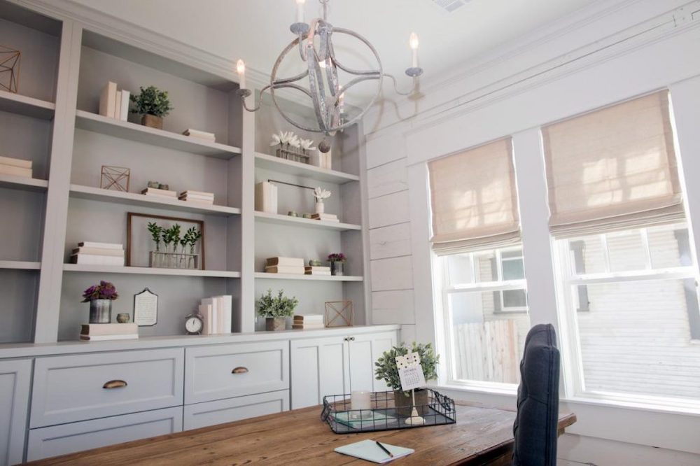 A modern farmhouse dining room with a large built in shelf unit filled with books, vases and pretty objects and a long wooden dining table