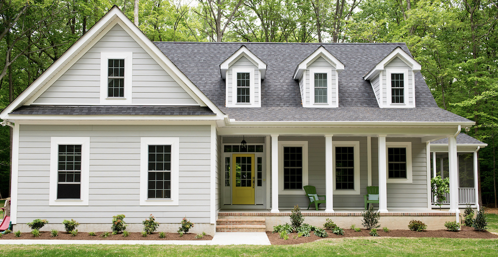 Cute grey cottage exterior painted in BEHR Hush PPU26-16 with white trim in BEHR Ultra Pure White® PPU18-06, and a yellow front door in Buzz-In P300-6