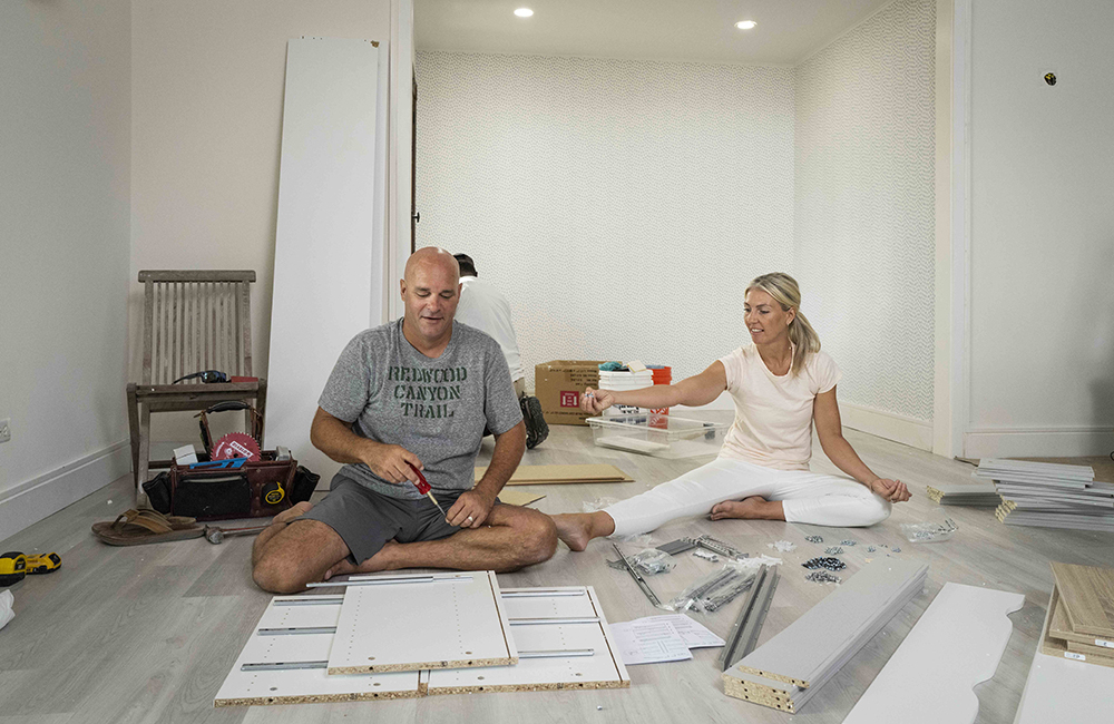 Bryan and Sarah Baeumler working on assembling furniture on set of Island of Bryan.