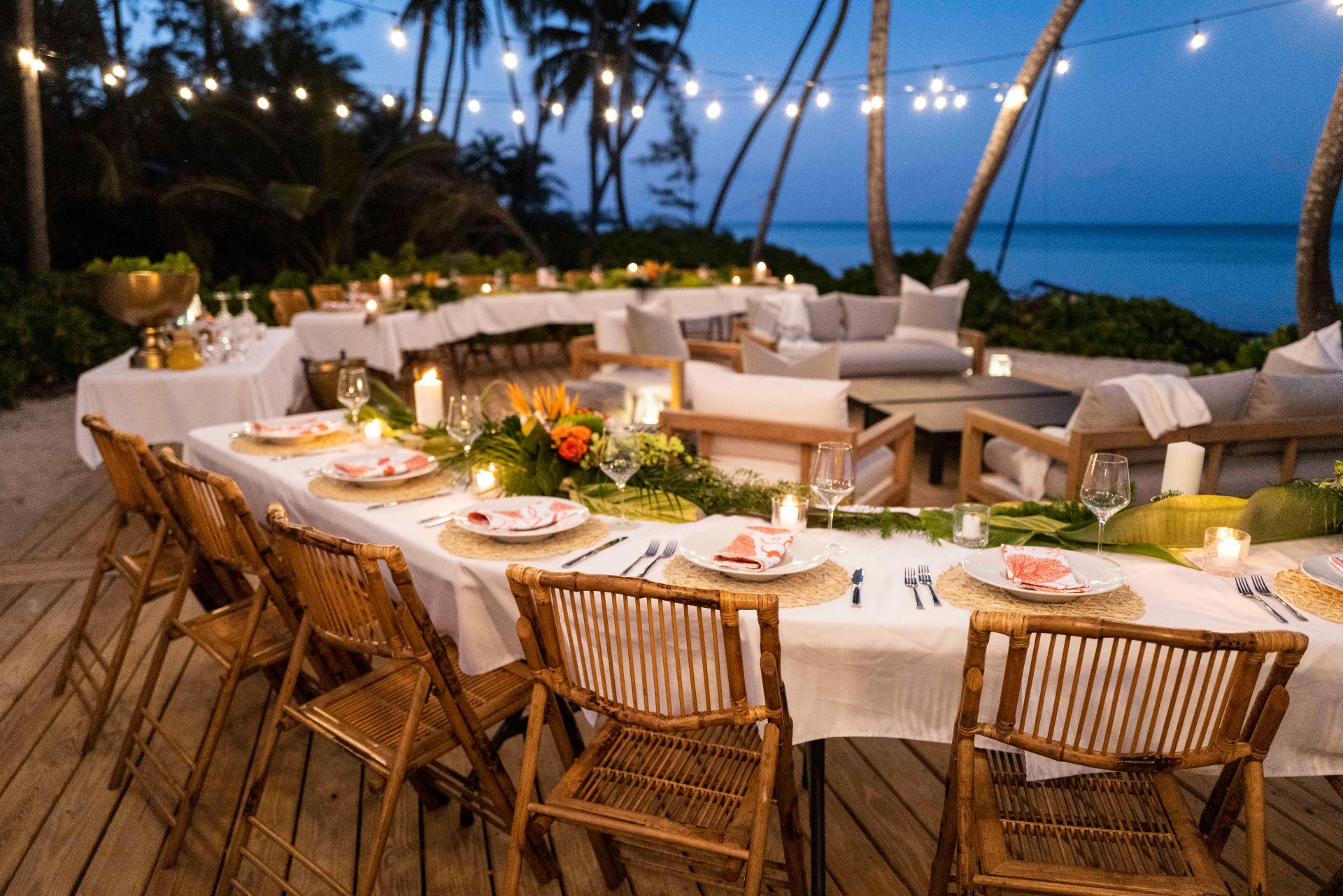 Outdoor dining deck facing the ocean with set tables and separate seating area