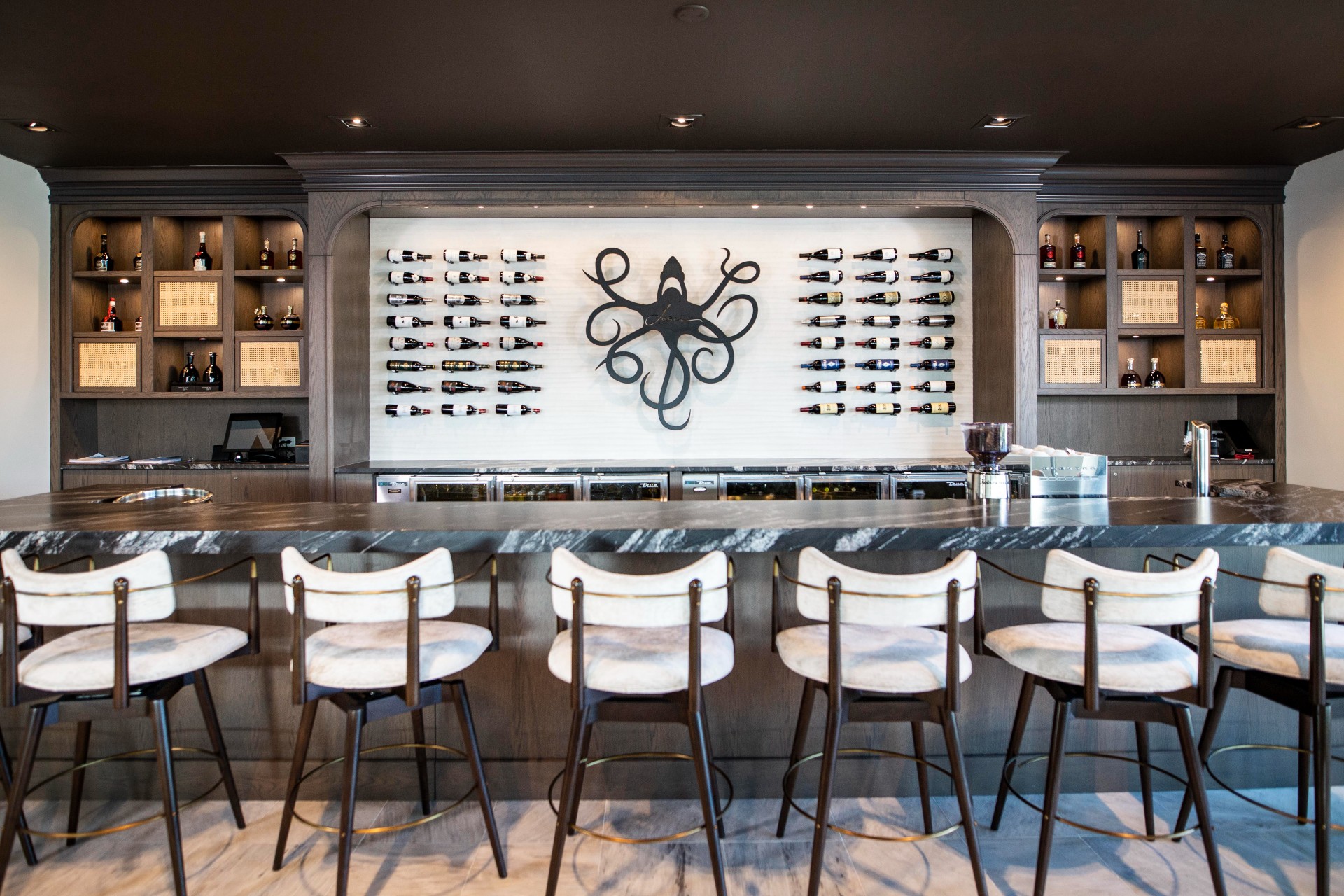 Restaurant bar with wine bottles and sculpture displayed on wall