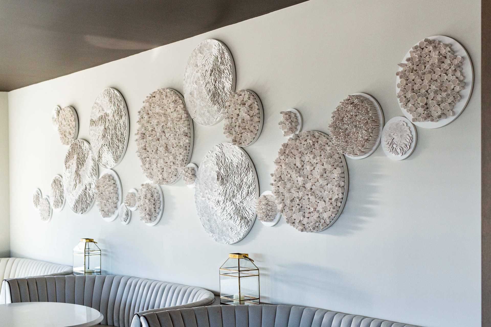 Circular artwork on white statement wall inside of restaurant