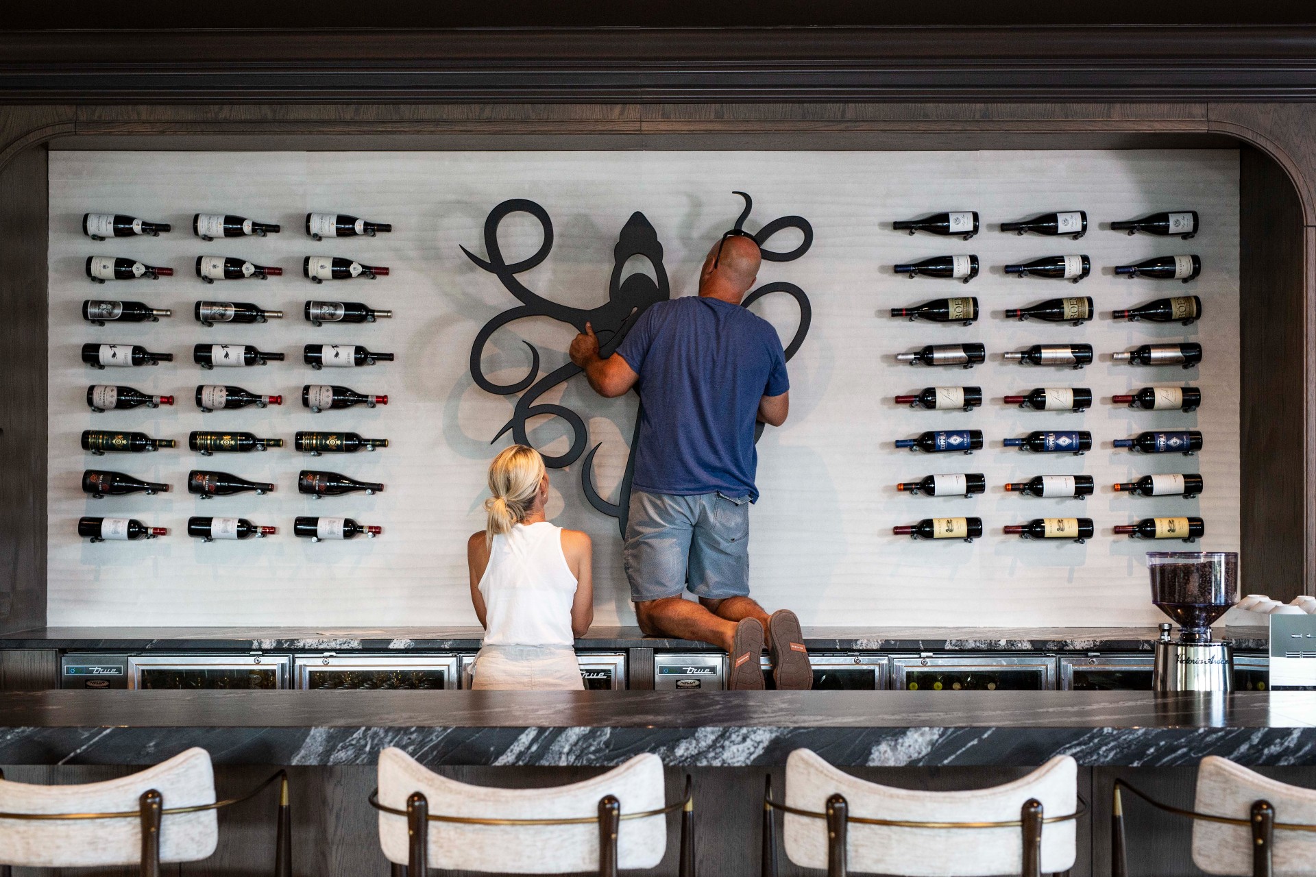 Bryan and Sarah installing art piece on wall at Lusca Restaurant