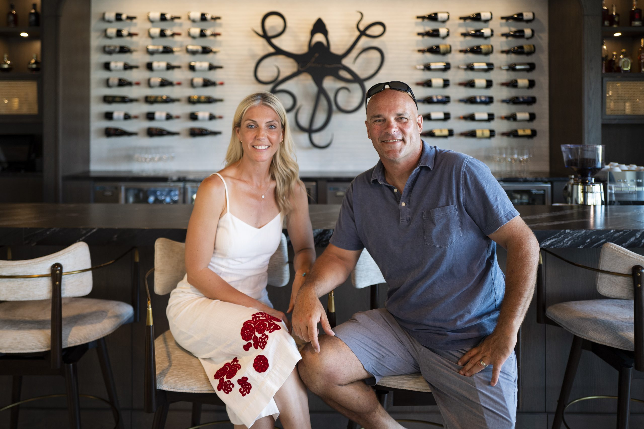 Sarah and Bryan seated at restaurant bar in front of custom sign