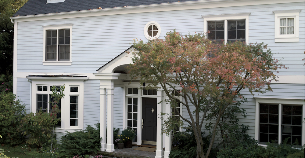 Exterior of a beautiful blue colonial style house painted in BEHR Ice Drop M530-1, with white trim in BEHR Ultra Pure White® PPU18-06 and the door in BEHR Black BLACK