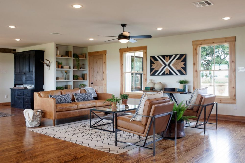 living room with two wood framed windows and tan leather furniture