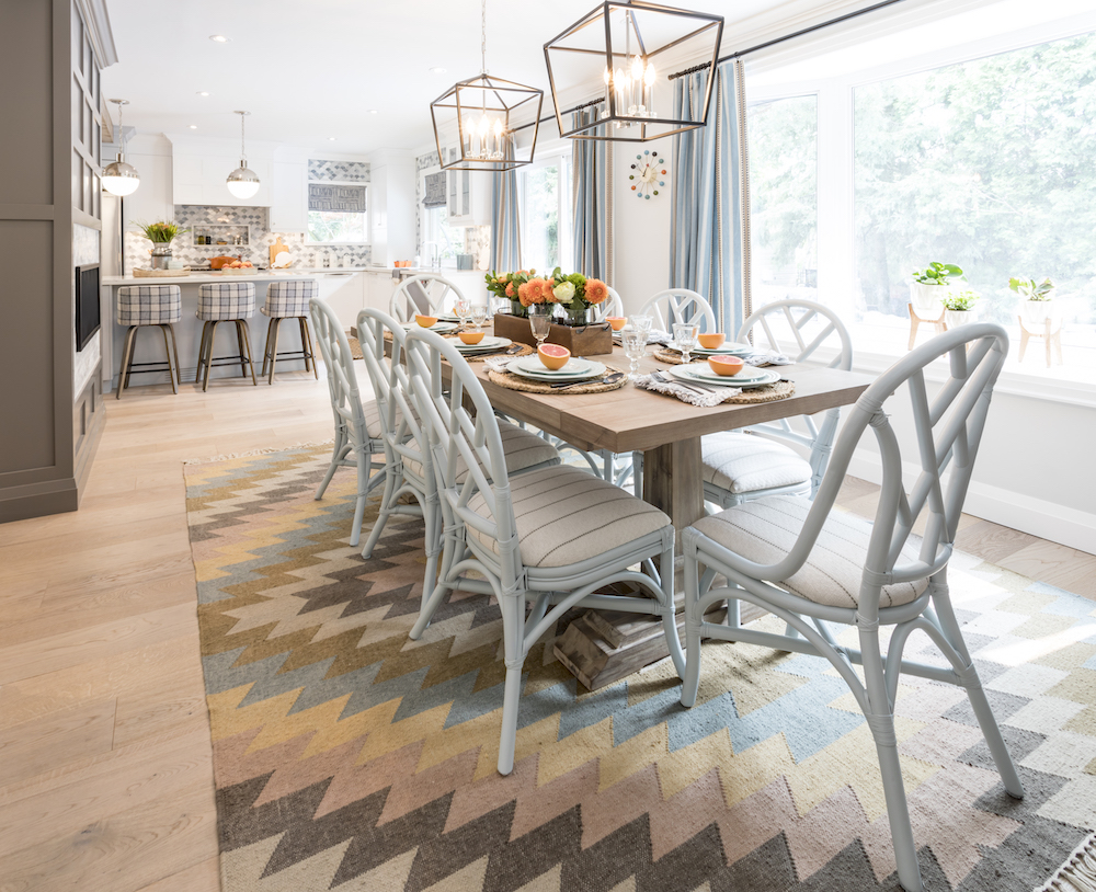 Ice blue rattan chairs surround a wooden harvest table set for a meal