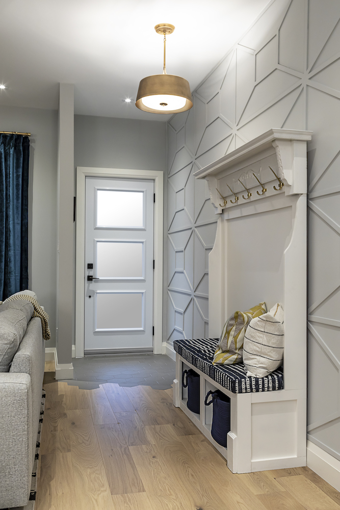 Front hall features modern wall panels and a moveable white bench seat and coat rack