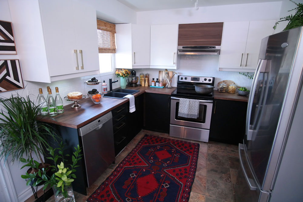 Small kitchen with wood counter, a black sink and coordinating dark lowers.