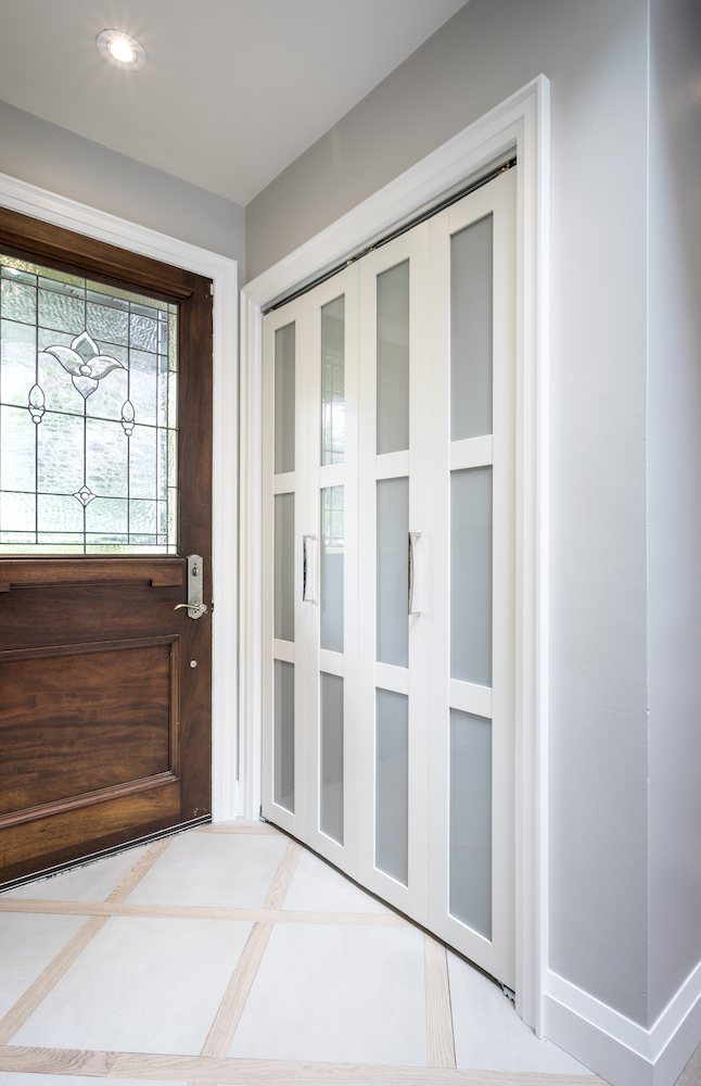 Newly renovated front entry with large grey tiles and new glass panelled closet doors