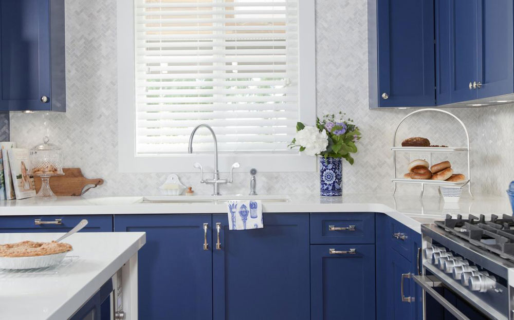 Country kitchen design with royal blue cabinets and grey/white herringbone tile backsplash.