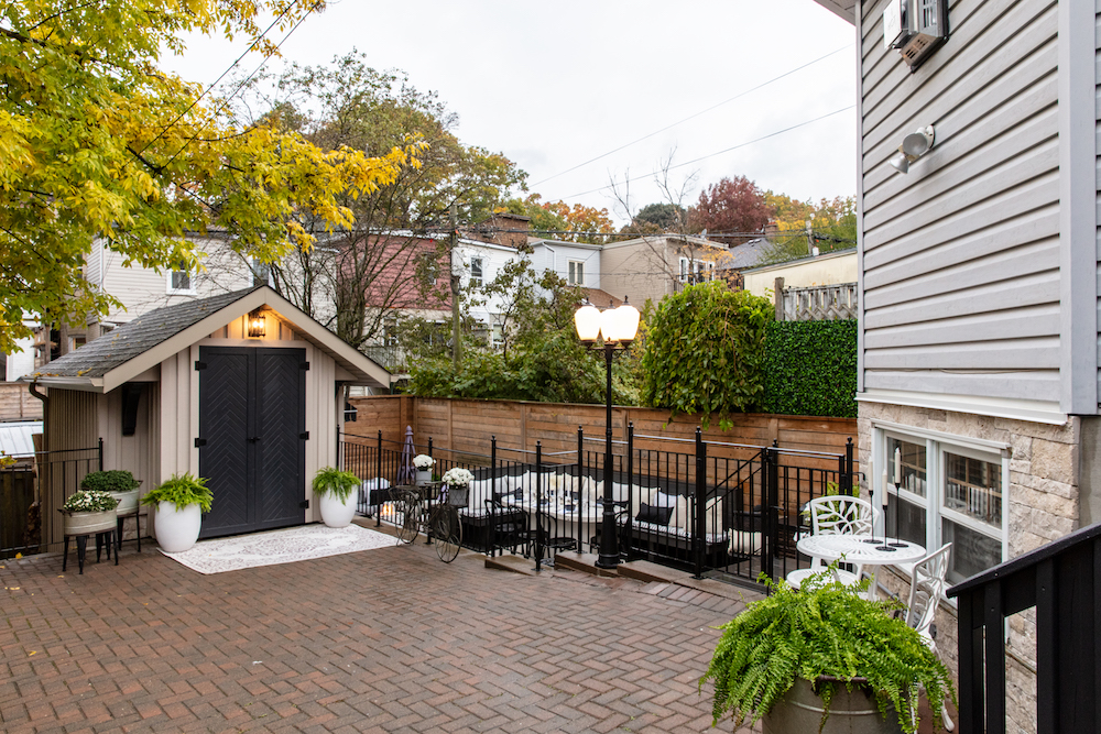 Parisian-inspired backyard with black fence, bike storage with herringbone doors and lamp post