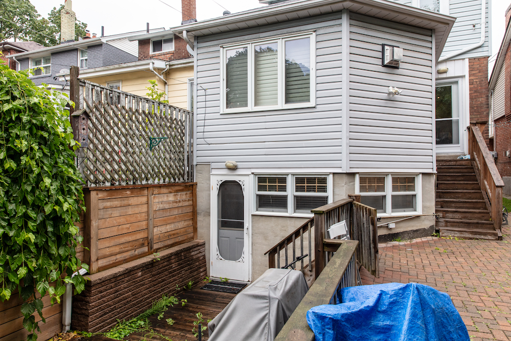 before back of house with rotting lower deck and wooden railings