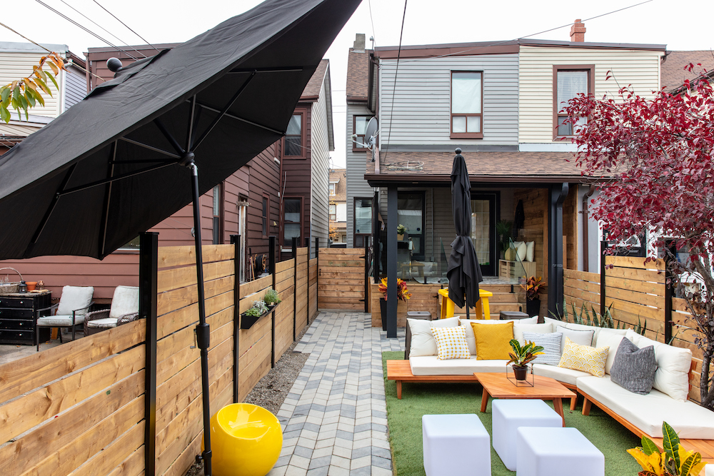 updated backyard with outdoor sectional, black umbrellas and green artificial turf