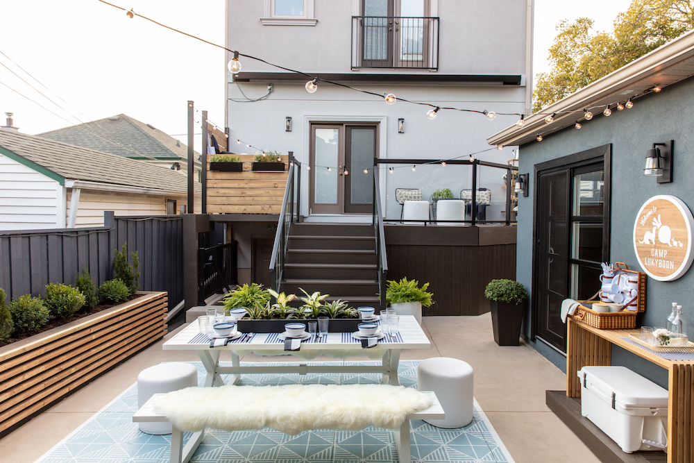 modern backyard with white outdoor dining area and deck with glass railings